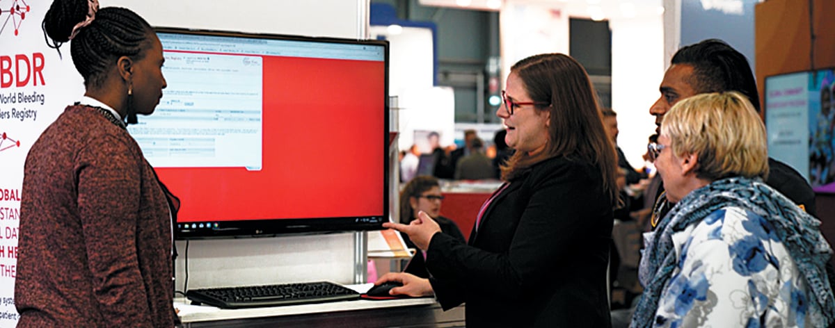 A woman shows information on a computer screen to two people observing