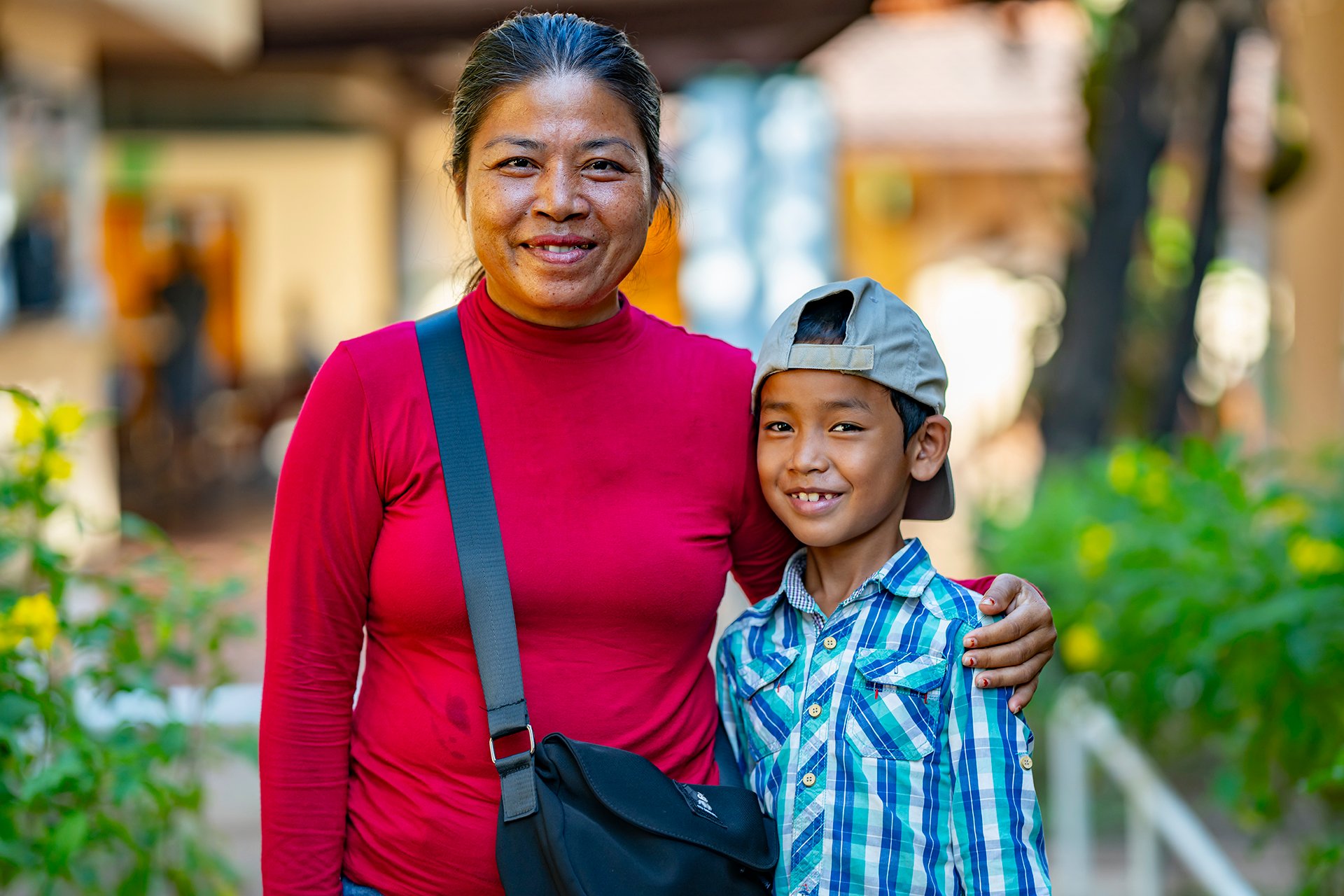 A mother smiles with her arm around her son.