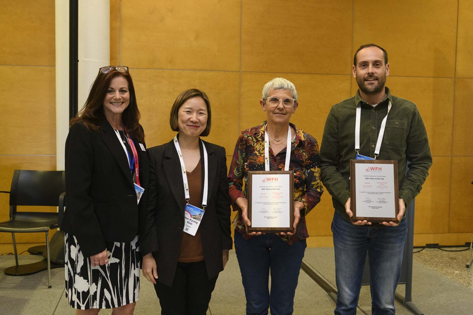 Twins of the year award winners from Rwanda and France smile and hold plaques.